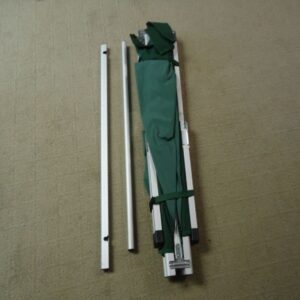 green rolled up cot with support legs laying on ground