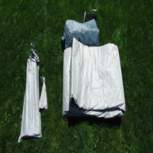 camping tent with poles and set up equipment laying on grass