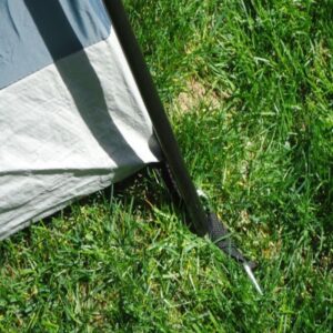 close up of tent pole and stake insert into ground